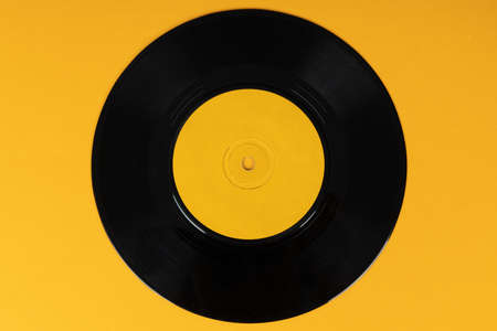Old vinyl disc on yellow background. Old vintage vinyl record.
