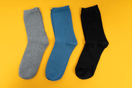 Pair of sock for clothing on yellow background. Set of long socks gray, blue and black,の写真素材