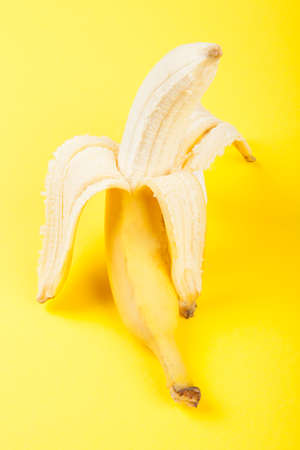 Half peeled banana on yellow backgroundの写真素材