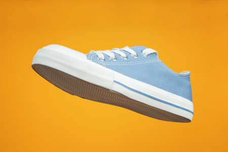 Sports shoe on yellow background. Sneaker or trainer. Fitness, sport, training concept.