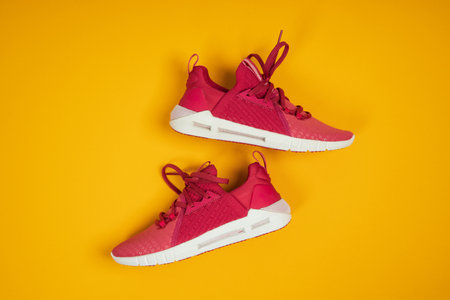 Pair of new pink sneakers, sport shoes on yellow background. Pink womens sport, running shoesの写真素材