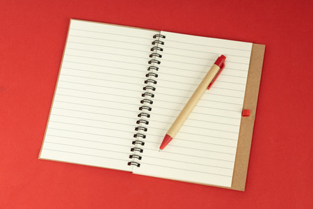 Set of recycle paper notebook and pen. Open diary notebook on red backgroundの写真素材