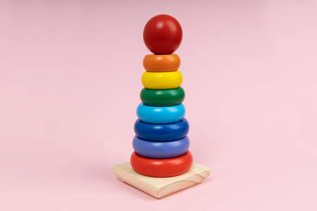 Multicolored wooden toy pyramid on pink background. Toy, build from colored wooden ringsの写真素材