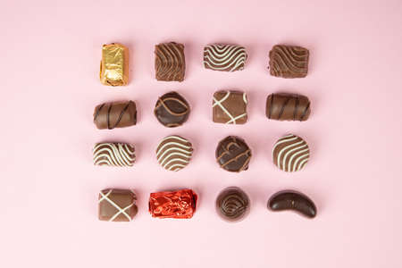 top view of various chocolate pralines on pink background. Collection chocolates candy. Assorted...