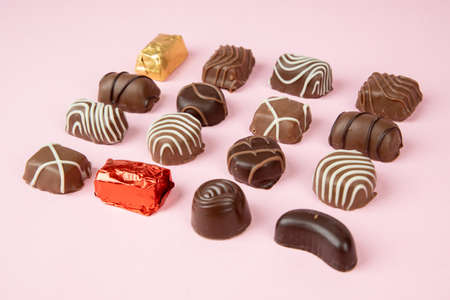 Various chocolate pralines on pink background. Collection chocolates candy. Assorted chocolates on...