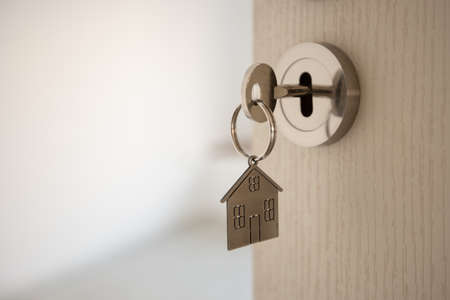 Open door to a new home with key and home shaped keychain. Mortgage, investment, real estate,...
