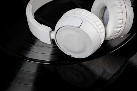 White wireless headphones on old vinyl records. Music concept. Rretro sound system