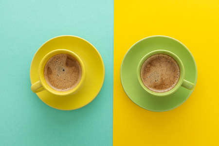 Two cups of coffee on blue and yellow background. Top view. Minimalism coffee concept.の写真素材
