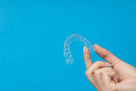 Woman hand holding Invisible tooth brackets. Dental healthcare and Orthodontic concept. Inivisalign braces or alignerの写真素材