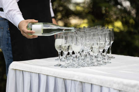 The waiter pours champagne in glasses. Wedding cateringの写真素材