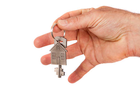 Man's hand giving a new metal key with home shaped keychain, isolated. New home concept