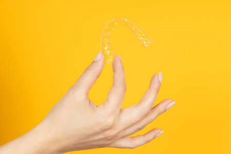 Woman hand holding Invisible tooth brackets. Dental healthcare and Orthodontic concept. Inivisalign...