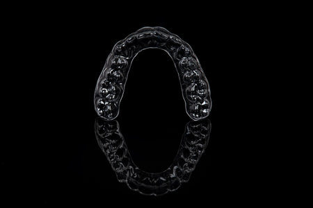 Invisible orthodontics cosmetic brackets on black background. Tooth aligners, for beautiful smile.