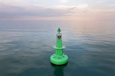 Large green buoy with solar panelsin the sea.