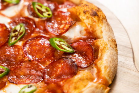 Close up of delicious italian pizza with salami on wooden boardの写真素材