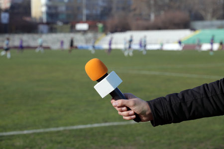 hand holding microphone for interview during a football machの写真素材