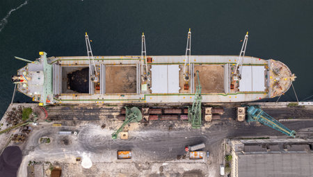 Loading dry cargo ship of brown sugar by cranes in port. Aerial view loading into holds of sea cargo vesselの写真素材