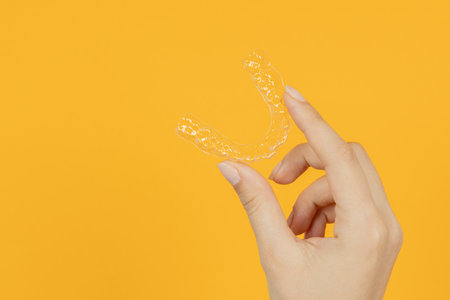 Woman hand holding Invisible tooth brackets. Dental healthcare and Orthodontic concept. Inivisalign...