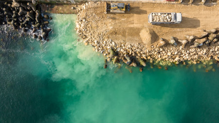 Aerial view of waterfront construction site with excavator. Bulldozer working on a breakwater constructionの写真素材