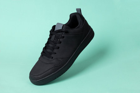 Black leather shoe on green background. Sport shoe, sneaker or trainer. Fitness, sport, training...
