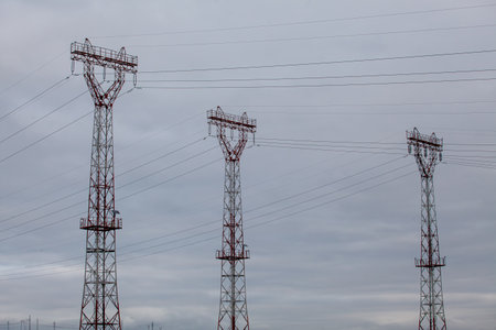Electricity pylons and cable lines against cloudy skyの写真素材