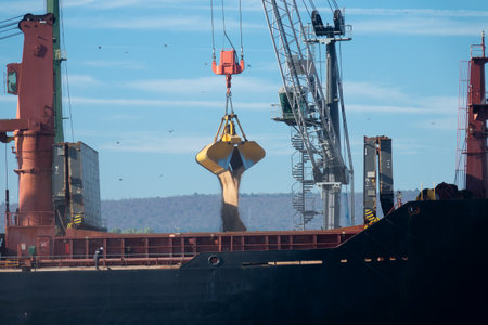 Loading dry cargo ship of wheat by cranes in port. Loading into holds of sea cargo vessel