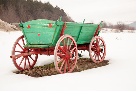 Old wooden cart. Green cart standing in the snowの写真素材