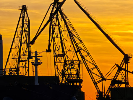 Industrial Port Cranes Silhouetted Against Sunset Sky. Maritime Logistics and Global Trade Conceptの写真素材