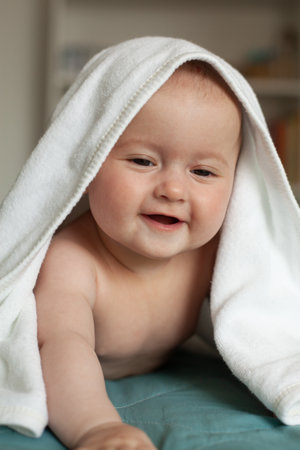 Little baby smiling, laughing.Cute baby lying on her tummy over a white towel.の写真素材