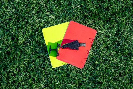 Red and Yellow Soccer Referee Cards with Whistle on Green Grass Field â Football Rules, Sports Discipline, and Game Control Conceptの写真素材