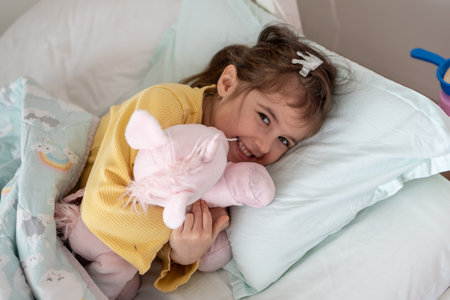 Morning awakening little child girl with her toy in bed. Happy girl in pajamas on bed right after awaking. Happy family conceptの写真素材