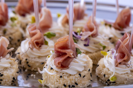 Gourmet canapÃ©s with prosciutto, cream cheese, and sesame seeds. Elegant finger food appetizers...
