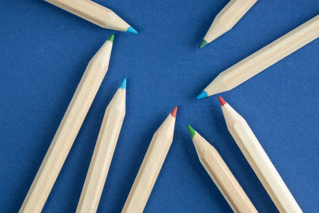 Wooden colored pencils arranged in a blue background. A minimalistic and artistic composition for creativity and education themes.の写真素材