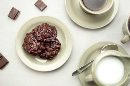Dark chocolate cookies served with coffee, milk and chocolate pieces.の写真素材