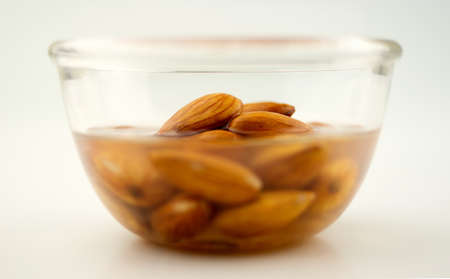 Almonds being soaked in a clear bowl, isolated on whiteの写真素材
