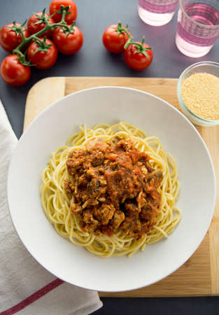 Bolognese sauce made with ground chicken served on top of spaghetti pasta in a white bowl. Aerial view with ingredients and condiments in the background.の写真素材