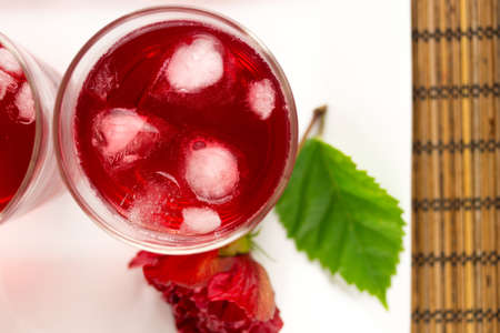 Rose and hibiscus flower iced tea served with ice cubesの写真素材
