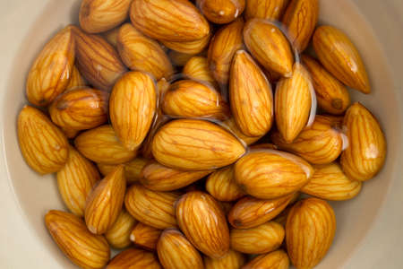 Macro view of almonds sitting in a bowl of water, being soaked to make almond milk.の写真素材