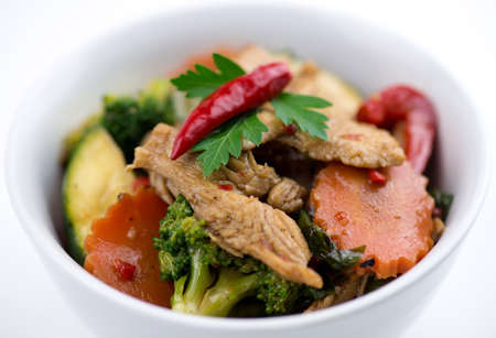 Thai chicken basil with carrot, zucchini, capsicum and broccoli in a white bowlの写真素材