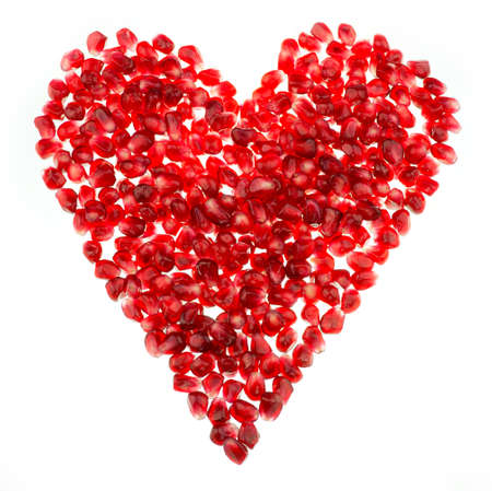 Pomegranate seed pile shaped like a heart isolated against a white backgroundの写真素材