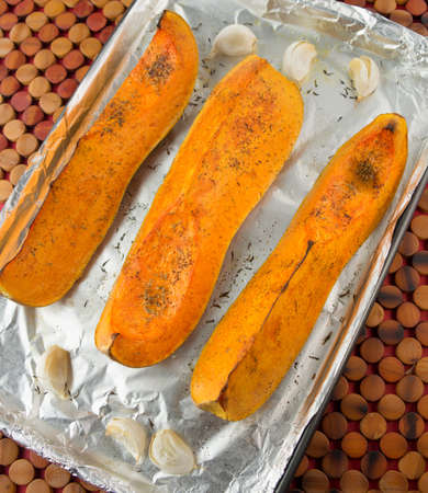Orange aquash on aluminum covered tray with garlicの写真素材