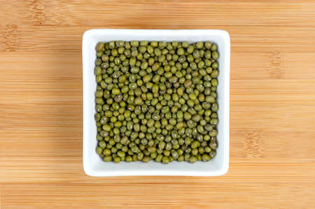 Green mung beans in white bowl on wooden boardの写真素材