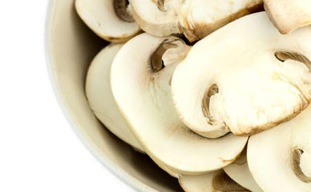 Macro closeup of sliced white common mushrooms in bowl isolated on whiteの写真素材