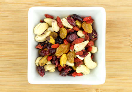 Mixed fruit and nuts in white bowl on wooden backgroundの写真素材