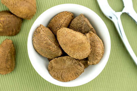 Brazil nuts in bowl with nut crackerの写真素材