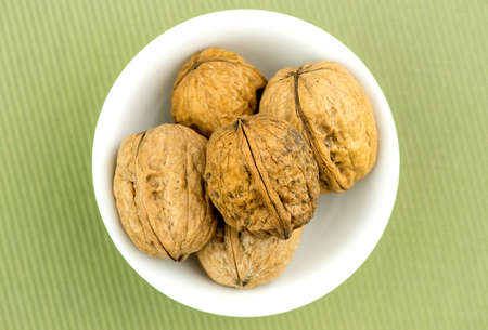 Walnuts in bowl on green backgroundの写真素材