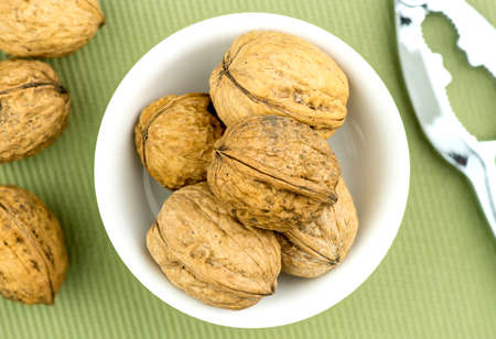 Walnuts in bowl with nut cracker nearbyの写真素材