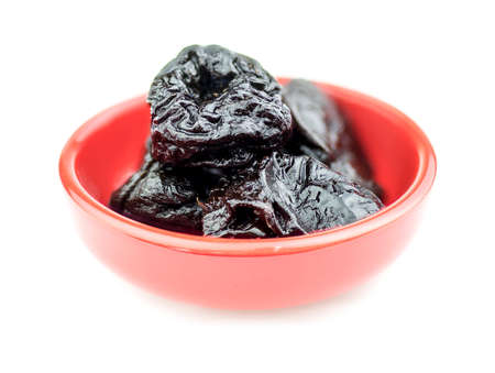 Bowl of pitted prunes isolated on whiteの写真素材