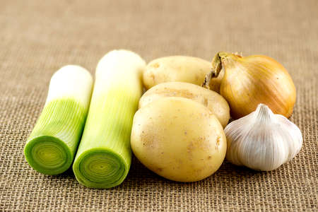 Fresh garlic, potato, leek and onion on burlap sackの写真素材