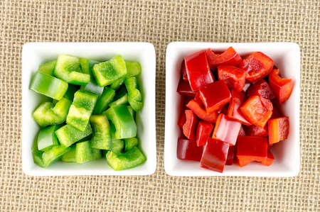 Bowls of green and red bell peppers against hessian backgroundの写真素材